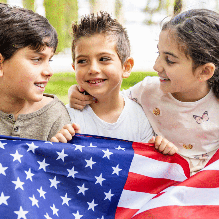 Three smiling bilingual children holding a U.S. flag outdoors