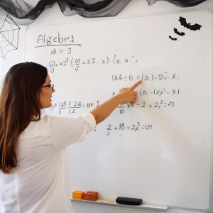 Algebra tutor teaching equations on a whiteboard decorated with Halloween bats, showing fun and effective math instruction.