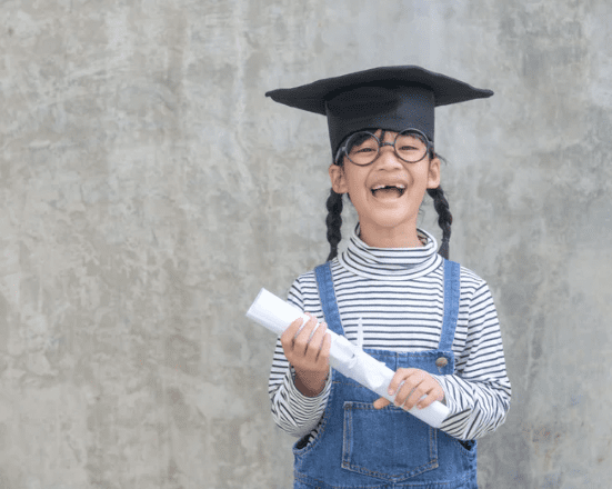 Smiling child in graduation cap holding a diploma